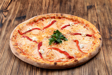Baked seafood pizza with melted cheese and ketchup on wooden background