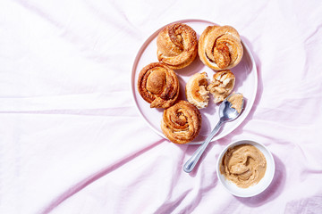 Trendy modern pastries cruffins (Croissant and Muffin) with cinnamon,brown sugar and vegan creamy nut cashew butter spread on pink textile background. Concept of breakfast or brunch.Top view, flat lay