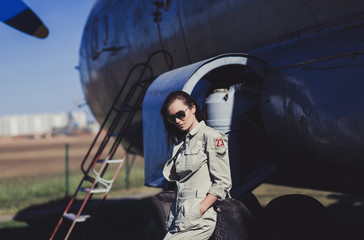 Military style model in fashion accessories and sunglasses near airplane