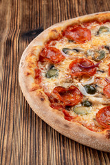 Very hot and spicy pizza with jalapeno, pepperoni and red onion on wooden background