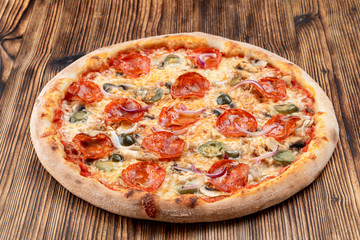 Very hot and spicy pizza with jalapeno, pepperoni and red onion on wooden background