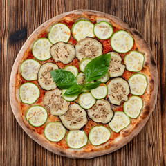 Baked vegetarian pizza with zucchini, eggplant and tomato sauce on wooden rustic table