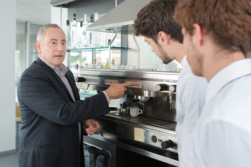 young waiters learning how to use coffee machine