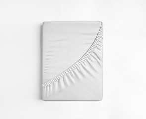 Flat sheet or bed cover folded. White fitted sheet isolated. White sheet with elastic band. - obrazy, fototapety, plakaty