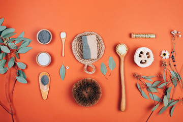 Collagen powder or white clay on orange background with Eucalyptus leaves . Flat lay style.