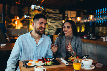 happy young couple having lunch in restaurant