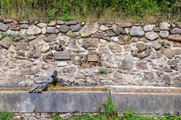 France. Arriège. Une fontaine où  coule de l'eau de source et son bassin en pierre. A fountain where spring water flows and its stone basin. 