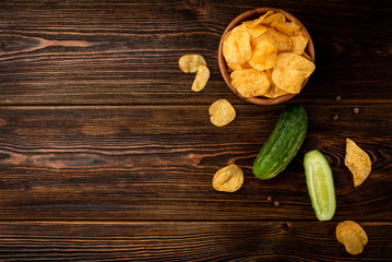 Crisps with cucumbers on dark wooden background.