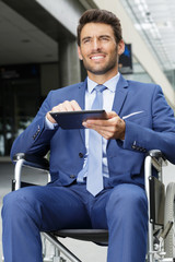 businessman sitting on wheelchair using a digital tablet