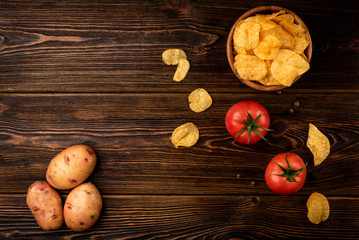 Crisps with tomato on dark wooden background.