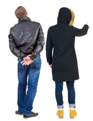 Back view of couple couple in winter jackets pointing.