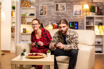 Gamers couple playing video games on the TV with wireless controllers in hands