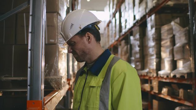 Stressed caucasian warehouse worker banging his head against rack
