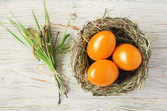 orange colored Easter eggs in nest top view background, selective focus image. Happy Easter card