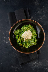 Pasta with pesto sauce on black plate. Top view
