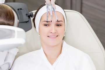 Top view young woman beauty master doing microblading on the eyebrows of a young pretty positive...