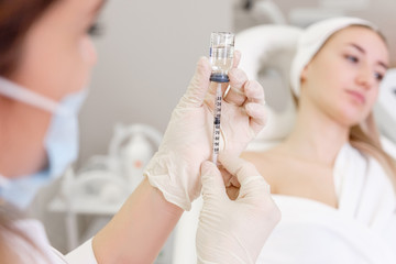 An unidentified immunologist picking up a vaccine into a vaccination syringe for a young female client. ?oncept of immunization against diseases and viruses. Medicine concept