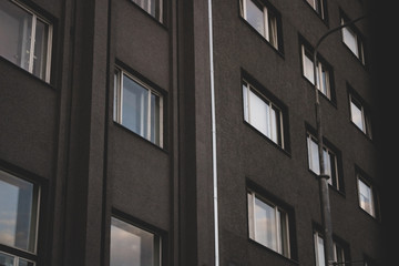 Urban landscapes of architectural buildings and numerous parks, with high contrast and brightness of paints; In the background cloud sky with sunset rays