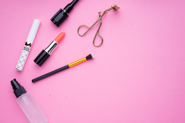 Creative arrangement of cosmetics products on pink background.