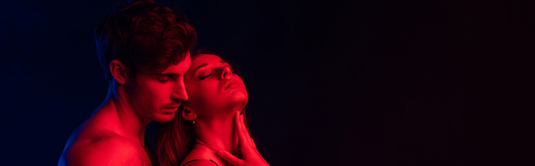passionate undressed sexy young couple in red light isolated on black, panoramic shot