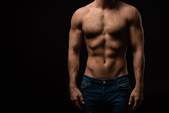 cropped view of sexy man in jeans with bare muscular torso isolated on black