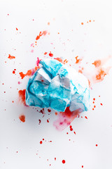crumpled blue paper on a white sheet with colored spots of watercolor