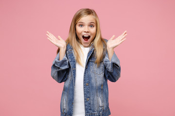 Excited little kid girl 12-13 years old in denim jacket isolated on pastel pink wall background...