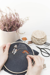 Girl making handmade embroidery. Young girl embroiders a pattern on the black material. Needlework. Sewing tool.