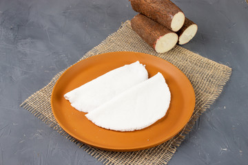 Tapioca, a traditional brazilian snack made from cassava flour. Cassava and dry coconut on the back. 