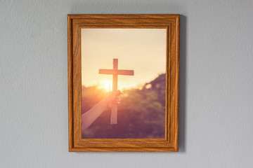 Fototapeta premium Close up woman hand holding wood cross or religion symbol shape over a sunset sky with clouds background for God,Christianity, religious, faith, holy, spiritual, Jesus, belief or resurrection.