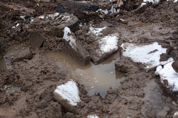 The texture of the black earth. Dirt on the street. Off-road from a mixture of clay and water. Traces of heavy equipment.