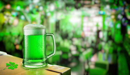 Glass of green beer stands on a table in a pub during the celebration of St. Patrick's Day.