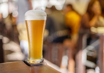 Glass of beer stands on a table in a pub. White unfiltered beer.