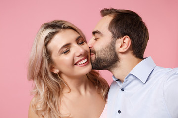 Close up of couple two guy girl in party outfit posing isolated on pastel pink background. Valentine's Day Women's Day birthday holiday concept. Kissing in cheeks doing selfie shot on mobile phone.