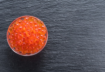 Red caviar in the bowl on gray graphite background. Top view.