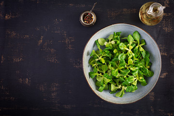Fresh leaves of corn salad in a bowl on a dark background. Vegetarian / vegan cuisine. Dietary food.
