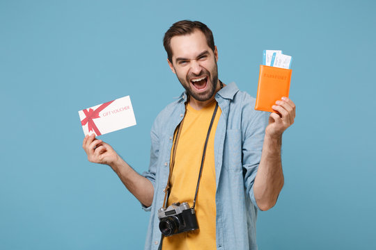 Joyful traveler tourist man in casual clothes with photo camera isolated on blue background. Passenger traveling on weekends. Air flight journey. Hold passport boarding pass ticket fan of cash money.
