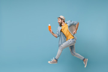 Side view of traveler tourist man in summer yellow clothes isolated on blue background. Male...