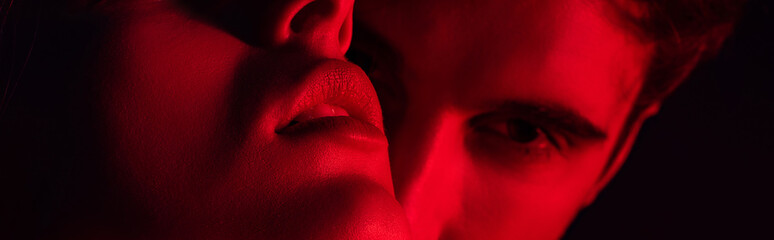 Fototapeta close up view of passionate young couple kissing in red light, panoramic shot obraz