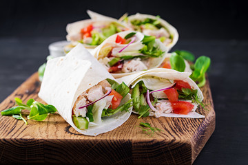 Fresh tortilla wraps with chicken and fresh vegetables on wooden board. Chicken burrito. Mexican food. Healthy food concept. Mexican cuisine.