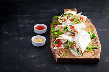 Fresh tortilla wraps with chicken and fresh vegetables on wooden board. Chicken burrito. Mexican food. Healthy food concept. Mexican cuisine.