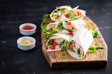 Fresh tortilla wraps with chicken and fresh vegetables on wooden board. Chicken burrito. Mexican food. Healthy food concept. Mexican cuisine.