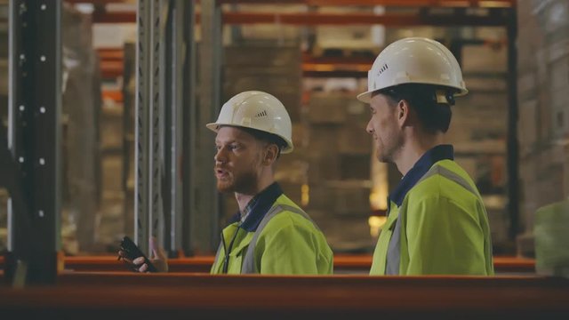 Two young supervisors inspecting industrial warehouse using barcode scanner
