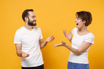 Funny young couple friends bearded guy girl in white t-shirts posing isolated on yellow orange...