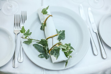 White holiday table setting decorated with green twig. Close-up.