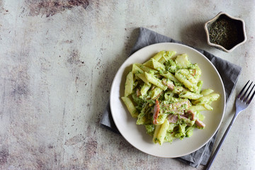 Spicy pasta with broccoli, cheese and ham on a beautiful plate on a gray background. Horizontal photo