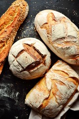 Bakery products. Crispy, beautiful bread on a dark background. Buckwheat, without yeast, wheat bread with flax and sunflower seeds. Top view, place for text.