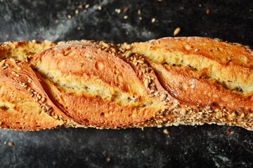 Bakery products. Crispy, beautiful bread on a dark background. Buckwheat, without yeast, wheat bread with flax and sunflower seeds. Top view, place for text.Tasty baguette. Close up