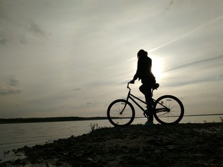 Fototapeta na wymiar silhouette of a girl on the bicycle on the beach
