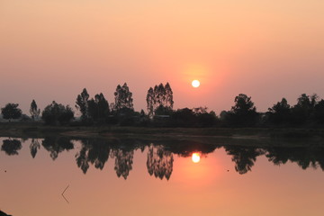  silhouette tree in asia with sunset.Tree silhouetted against a setting sun.Dark tree on open field dramatic sunrise and reflection in water.